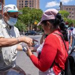 Un grupo de mujeres jornaleras inmigrantes reciben comida mientras esperan ser contratadas para trabajos de limpiezas, el 29 de junio de 2022 en la plaza de un vecindario judío hasídico de Brooklyn en Nueva York (EE. UU). EFE/Ángel Colmenares