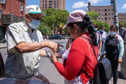 Un grupo de mujeres jornaleras inmigrantes reciben comida mientras esperan ser contratadas para trabajos de limpiezas, el 29 de junio de 2022 en la plaza de un vecindario judío hasídico de Brooklyn en Nueva York (EE. UU). EFE/Ángel Colmenares