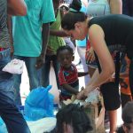 Una mujer entrega bebidas y alimentos a varios migrantes en Paso Canoas (Panamá).Imagen de archivo. EFE / Marcelino Rosario