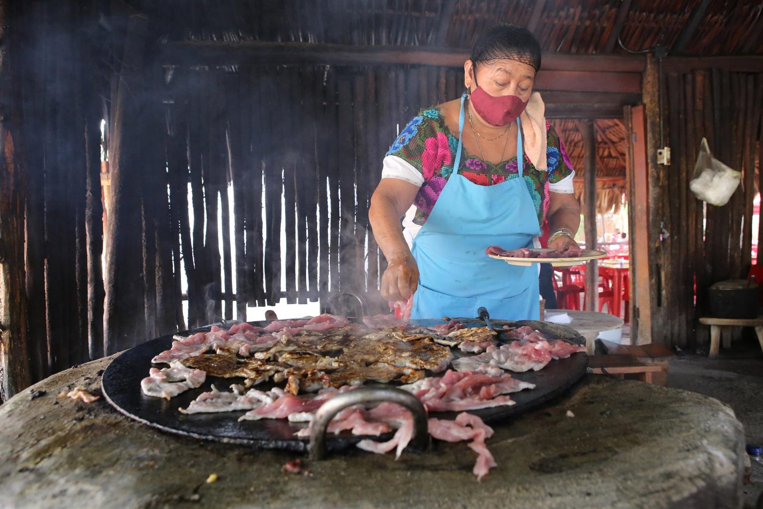 Una mujer prepara poc chuc, carne de cerdo aderezada en el restaurante La Tía de Kaua, el 23 de julio de 2022 en el poblado de Tikuch, Valladolid, estado de Yucatán (México). EFE/Lourdes Cruz