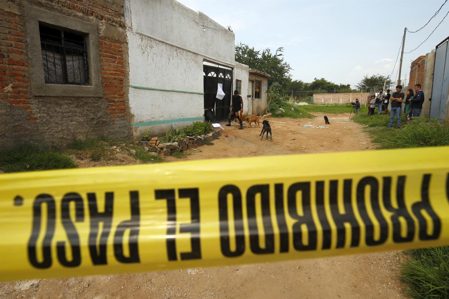 Personas observan el exterior de un centro de rehabilitación donde la madrugada de hoy, un grupo armado ejecuto a cinco hombres y una mujer, en la ciudad de Tlaquepaque, estado de Jalisco (México). EFE/ Francisco Guasco