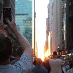 Un grupo de personas toman fotografías a la puesta del sol entre edificios hoy, en una calle de Manhattan en Nueva York (EEUU). EFE/ Sarah Yáñez-Richards