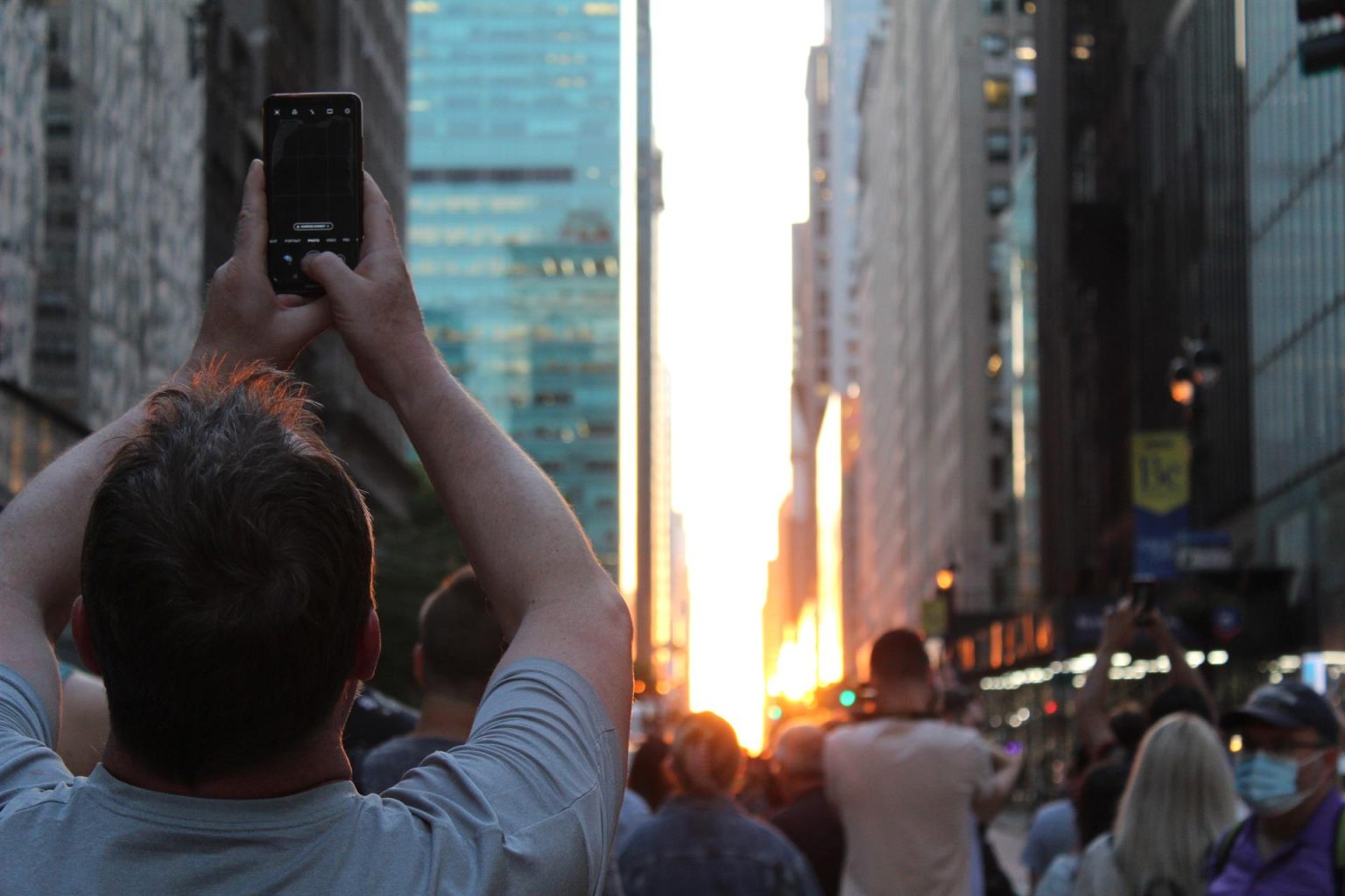 Un grupo de personas toman fotografías a la puesta del sol entre edificios hoy, en una calle de Manhattan en Nueva York (EEUU). EFE/ Sarah Yáñez-Richards