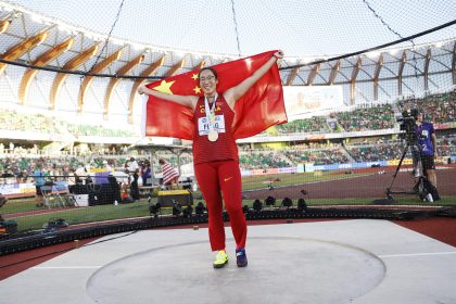 La medallista de oro Bin Feng de China posa para fotos con su medalla y bandera nacional después de la final de lanzamiento de disco femenino, durante el Campeonato Mundial de Atletismo Oregon, en Hayward Field, Estados Unidos. EFE/EPA/Robert Ghement