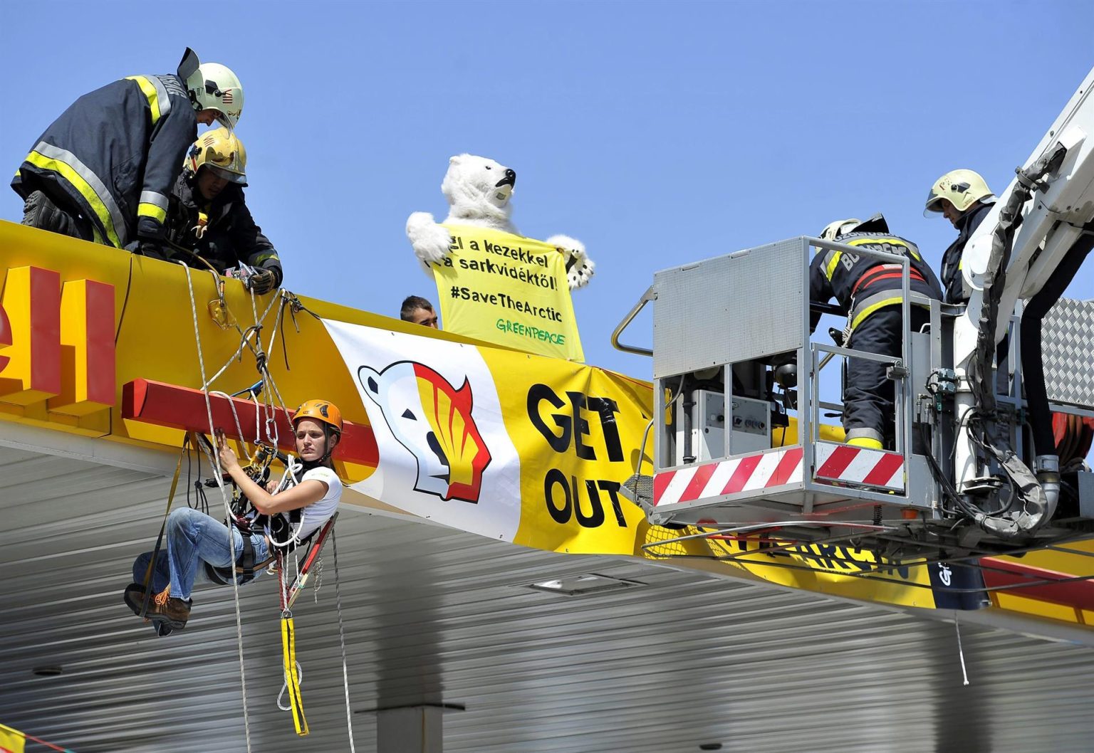 Fotografía de archivo fechada el 19 julio de 2012 donde aparecen unos bomberos mientras bajan a una activista de Greenpeace desde el techo de una gasolinera de Shell junto a otro activista disfrazado de oso polar, durante una manifestación en Budapest (Hungría). EFE/EPA/ Tibor Illyes