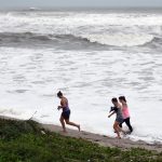 Curiosos caminan cerca de las olas en el paseo marítimo de Juno Beach, Florida (Estados Unidos). Imagen de archivo EFE/ Jim Rassol