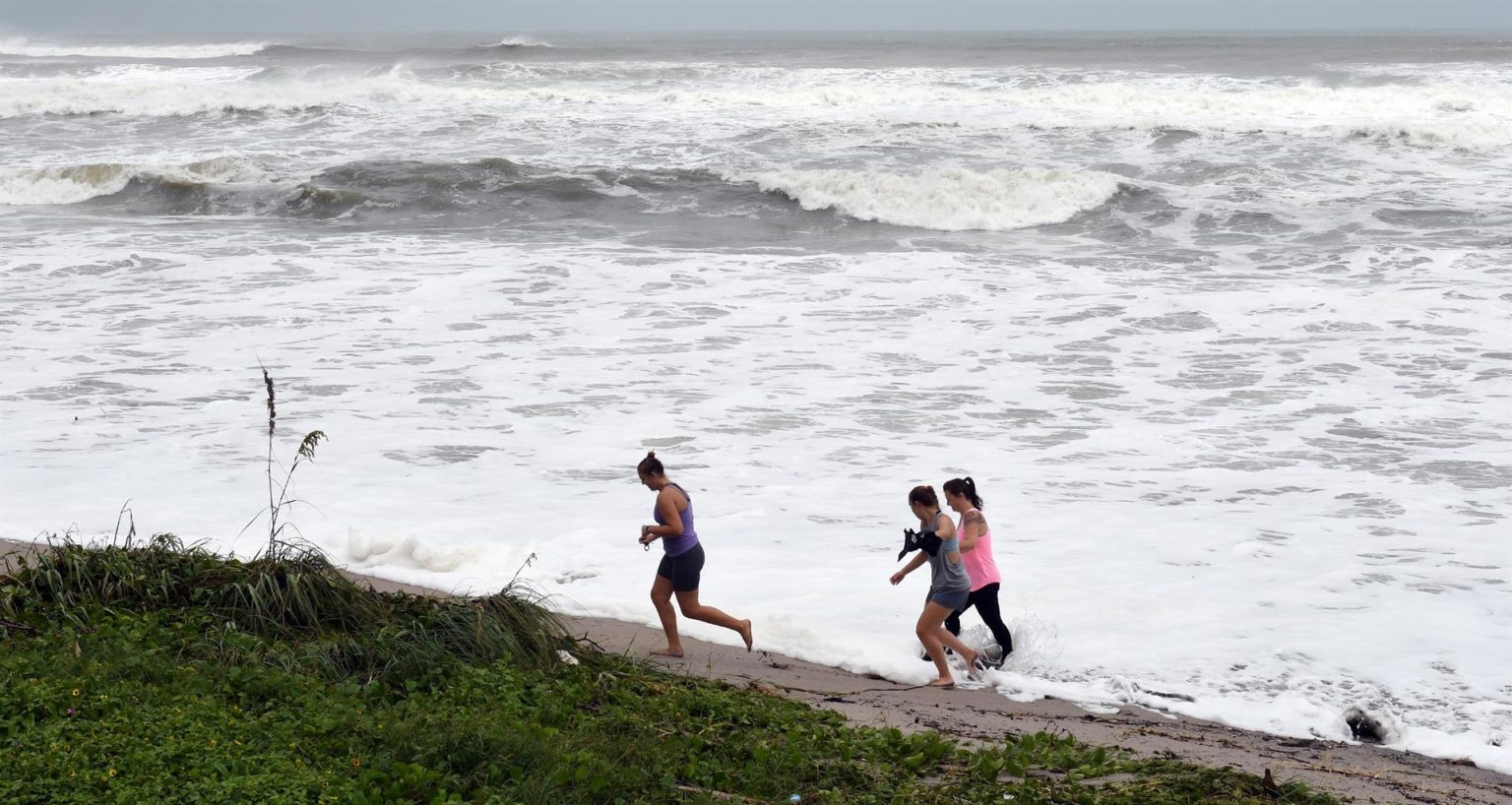 Curiosos caminan cerca de las olas en el paseo marítimo de Juno Beach, Florida (Estados Unidos). Imagen de archivo EFE/ Jim Rassol