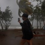 Fotografía de archivo de una mujer grabando las fuertes olas y la velocidad del viento en Puerto Rico. EFE/ Thais Llorca
