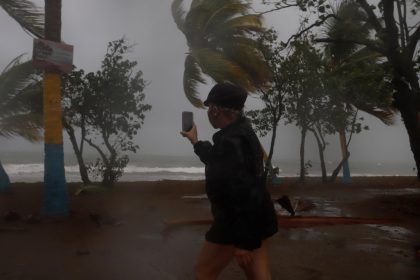 Fotografía de archivo de una mujer grabando las fuertes olas y la velocidad del viento en Puerto Rico. EFE/ Thais Llorca