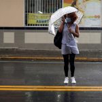 Fotografía de archivo de una mujer usando una sombrilla mientras cruza una calle en San Juan (Puerto Rico). EFE/Thais Llorca