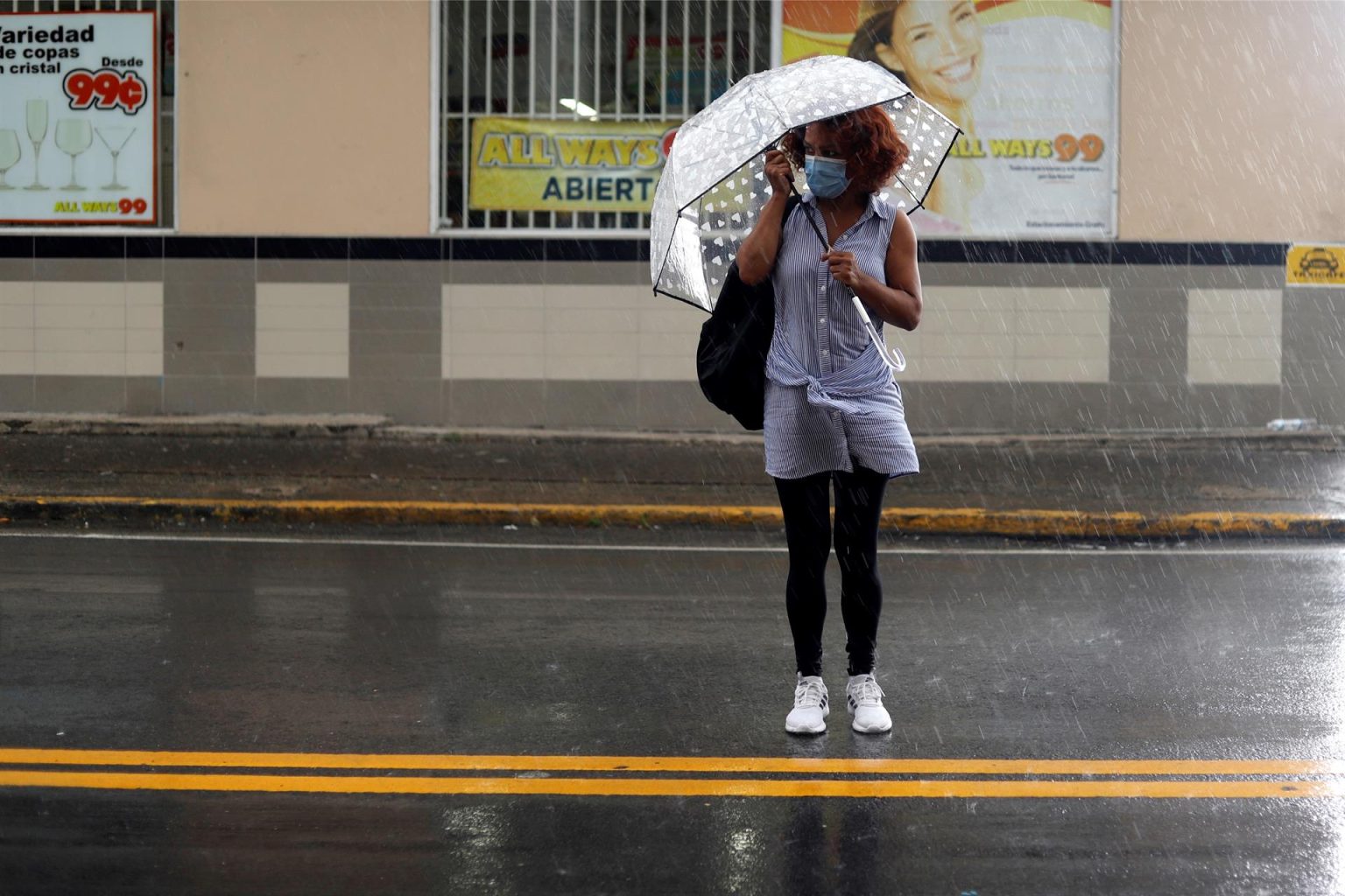 Fotografía de archivo de una mujer usando una sombrilla mientras cruza una calle en San Juan (Puerto Rico). EFE/Thais Llorca