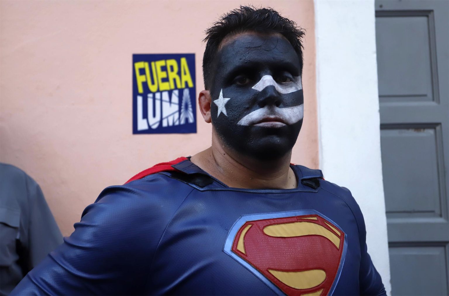 Un hombre con el rostro pintado de la bandera puertorriqueña en negro y disfrazado de Superman participa en una protesta en contra de Luma Energy, la empresa privada encargada de la transmisión y distribución de la electricidad en Puerto Rico, hoy, frente a la Fortaleza, sede del Ejecutivo en San Juan (P.Rico). EFE/ Thais Llorca