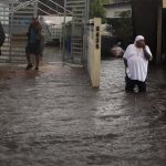 Personas caminan en una calle inundada debido a lluvias ocasionadas por el paso del huracán Fiona en Toa Baja (Puerto Rico). EFE/Thais LLorca