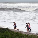 Fotografía de archivo de curiosos que caminan cerca de las olas que causa un huracán en el paseo marítimo de Juno Beach, Florida (Estados Unidos). EFE/ Jim Rassol