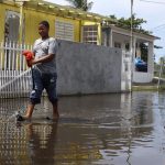 Jovani Correa (i) y Mariel Laureano intentan atrapar peces vivos que quedaron acumulados en una calle inundada tras el paso del huracán Fiona, hoy, en Loíza (Puerto Rico). EFE/ Thais Llorca