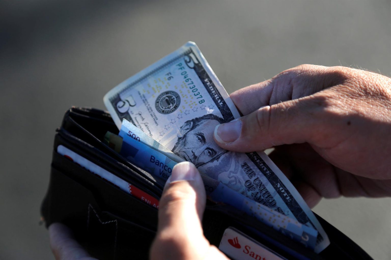 Fotografía de archivo que muestra una persona guardando en su cartera un billete de cinco dólares en Tepatitlán, estado de Jalisco (México). EFE/ Francisco Guasco