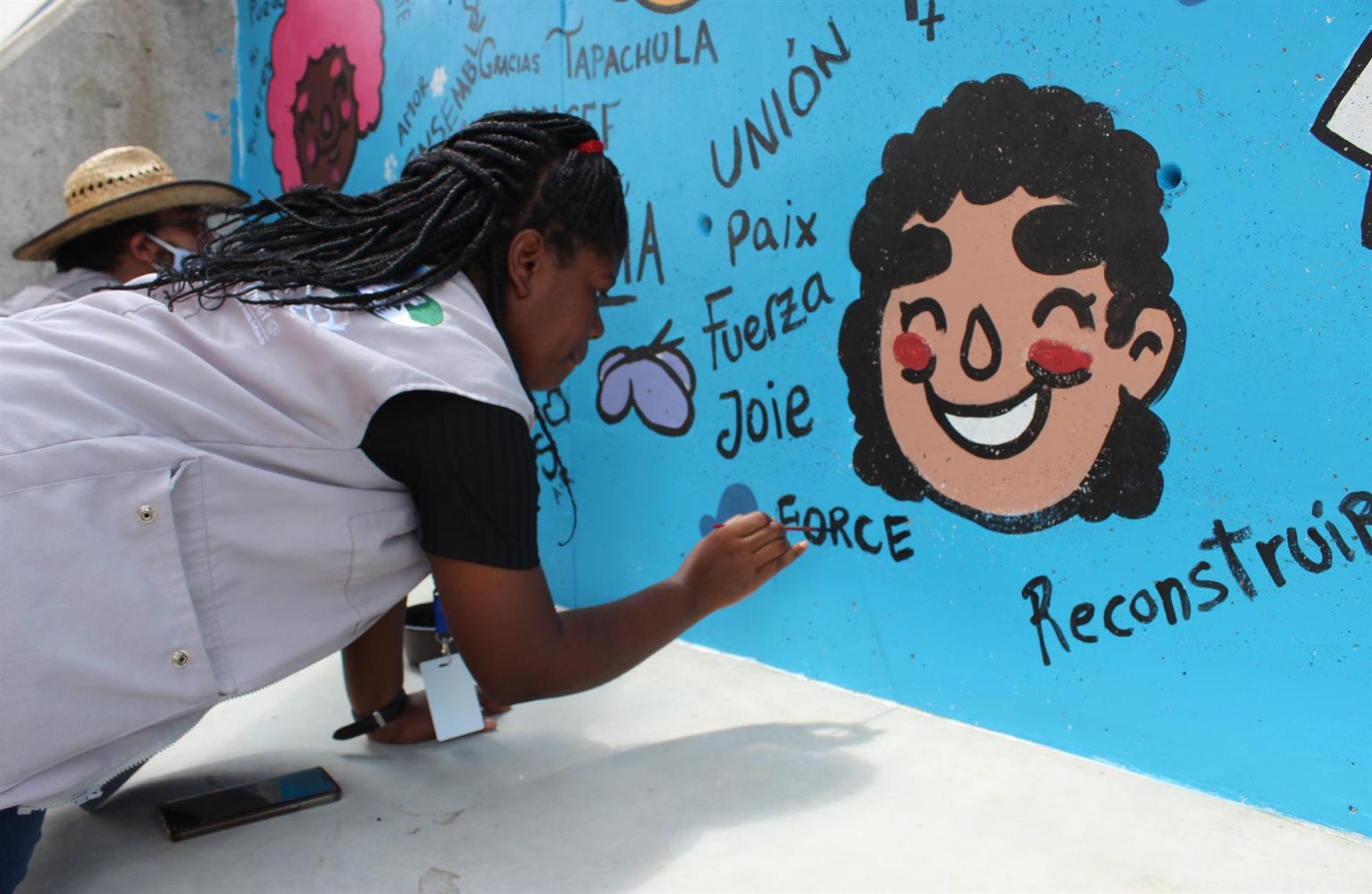 Una migrante psicóloga haitiana pinta hoy, un mural en una antigua instalación de ferrocarriles donde se ha edificado un Centro de Desarrollo Comunitario (CEDECO) en la ciudad de Tapachula, en el estado de Chiapas (México). EFE/Juan Manuel Blanco