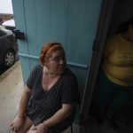 Joeni Rodríguez se reúne con sus vecinos en la puerta de su casa, tras quedarse sin luz por el paso del huracán Fiona hoy, en San Juan (Puerto Rico). EFE/ Thais Llorca