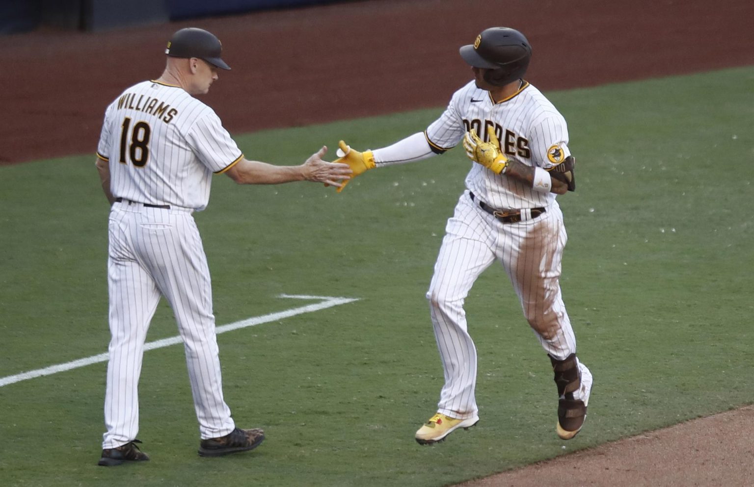 Manny Machado (d), tercera base de los Padres de San Diego, fue registrado este miércoles, 19 de octubre, al ser felicitado por el entrenador de base Matt Williams (i), luego de que le anotara un jonrón solitario a los Filis de Filadelfia, durante el segundo partido de la Serie de Campeonato de la Liga Americana de la MLB, en el estadio Petco Park, en San Diego (California, EE.UU.). EFE/Caroline Brehman