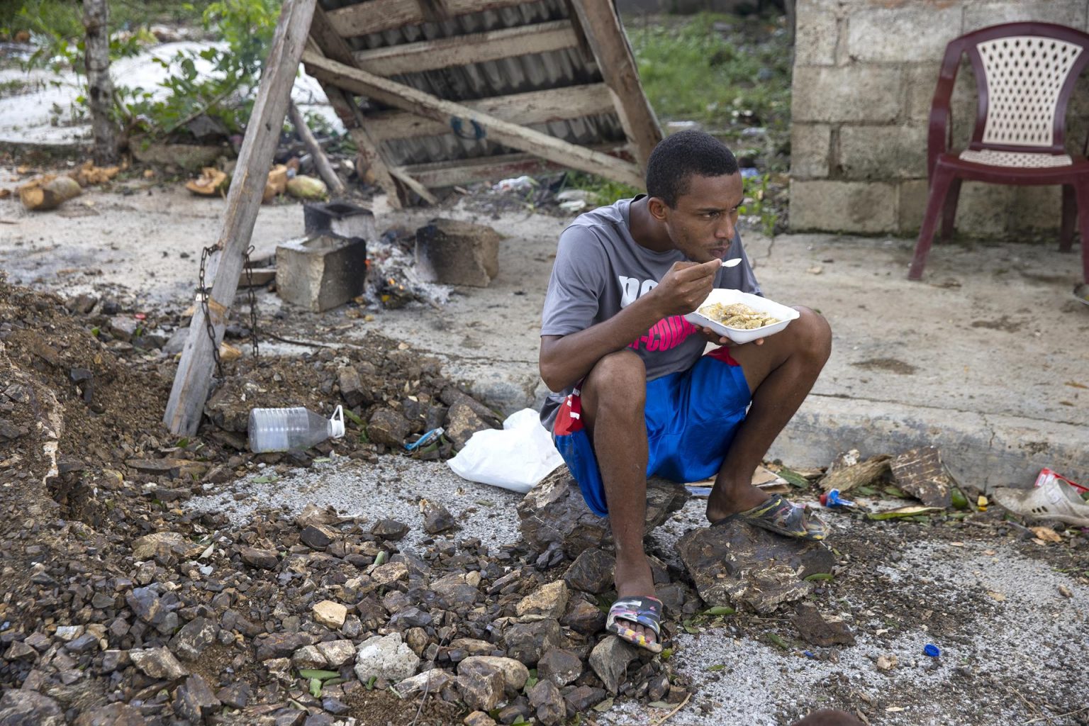 Un hombre come sentado sobre unos escombros tras el paso del huracán Fiona en el barrio Ginandiana, en El Seibo (República Dominicana). EFE/ Orlando Barría