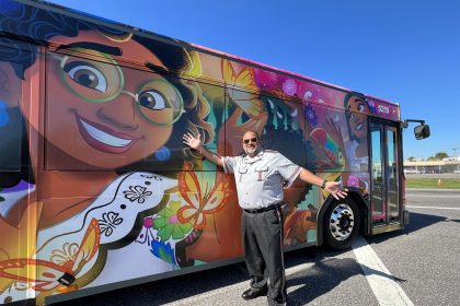 Fotografía cedida por Disney donde se muestra a un conductor mientras señala a un autobús decorado con personajes de la película "Encanto". Los visitantes de Disney World, el complejo de parques temáticos de Disney en Orlando (Florida), se desplazarán estos días por sus instalaciones a bordo de autobuses decorados con motivos de la película animada "Encanto" para honrar el Mes de la Herencia Hispana. EFE/Disney /SOLO USO EDITORIAL /NO VENTAS /SOLO DISPONIBLE PARA ILUSTRAR LA NOTICIA QUE ACOMPAÑA /CRÉDITO OBLIGATORIO