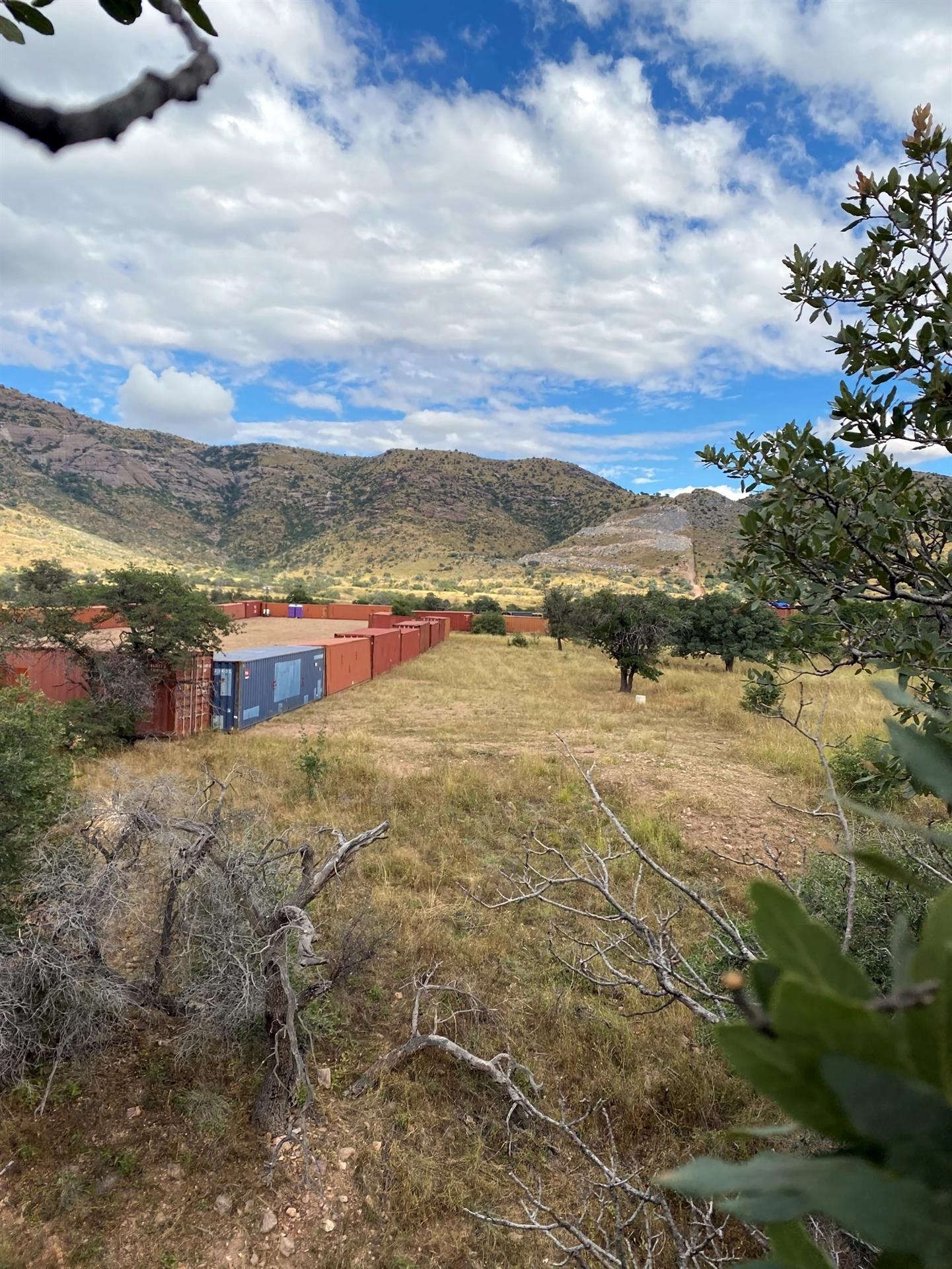 Fotografía cedida por el Centro para la Diversidad Biológica donde se aprecian unos contenedores depositados en un descampado frente a las montañas Huachuca, visiblemente dañadas por la construcción del muro fronterizo durante la era Trump, en la frontera entre Arizona y México en el Bosque Nacional Coronado cerca de Tucson, Arizona. EFE/Center for Biological Diversity /SOLO USO EDITORIAL /NO VENTAS /SOLO DISPONIBLE PARA ILUSTRAR LA NOTICIA QUE ACOMPAÑA /CRÉDITO OBLIGATORIO