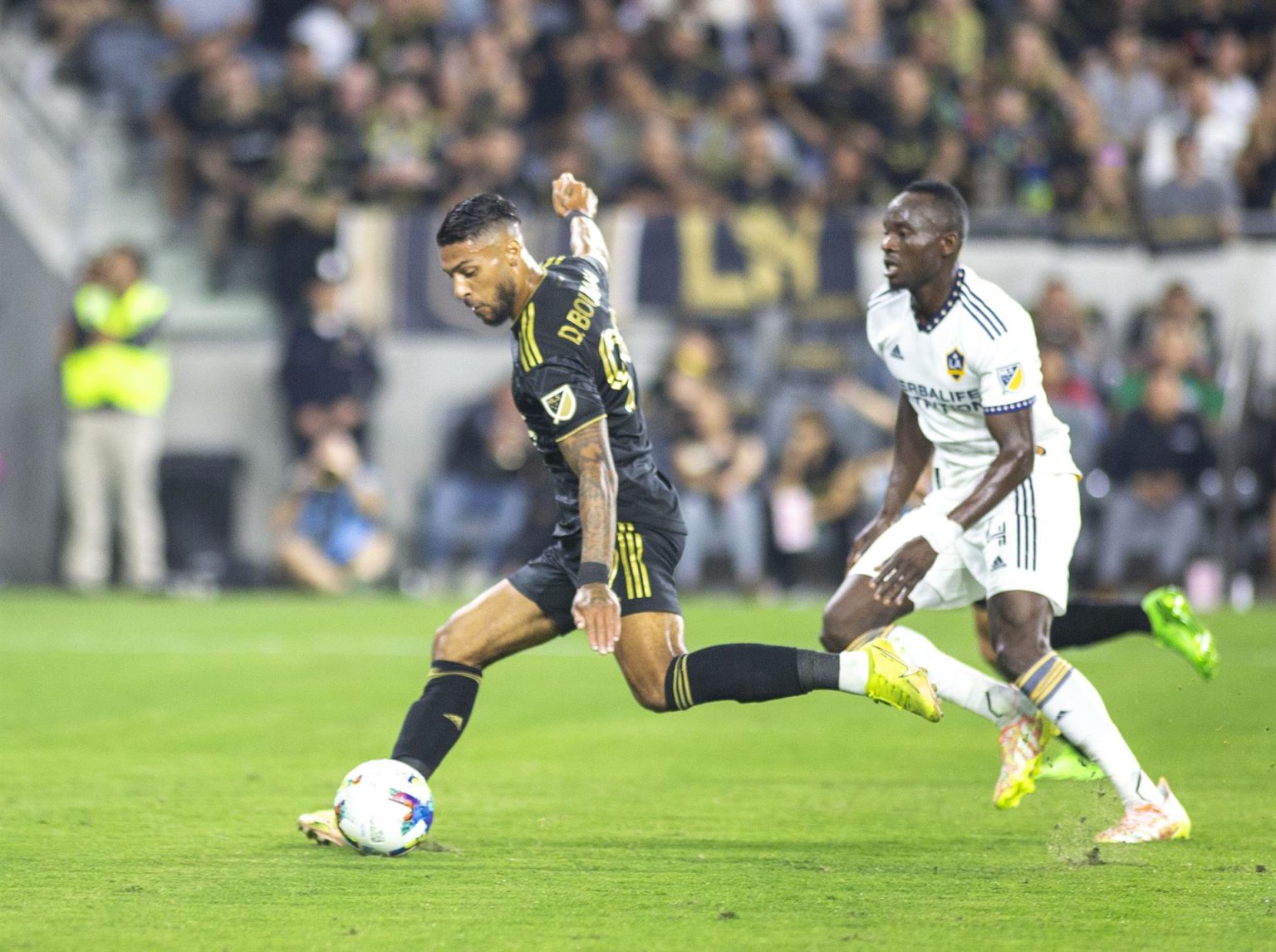 Denis Bouanga (i) de Los Ángeles Galaxy en acción ante Los Ángeles FC, hoy, durante un partido de los play off de la conferencia oeste, disputado en el Banc one stadium,en Los ángeles (Estados Unidos). EFE/ Armando Arorizo