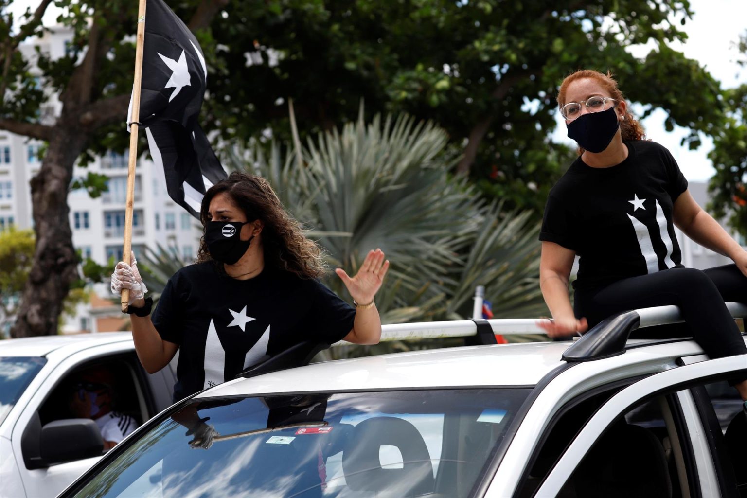 Imagen de archivo que muestra a dos personas vestidas de negro ondeando la bandera puertorriqueña en negro desde las ventanas de un auto en San Juan (Puerto Rico). EFE/Thais Llorca