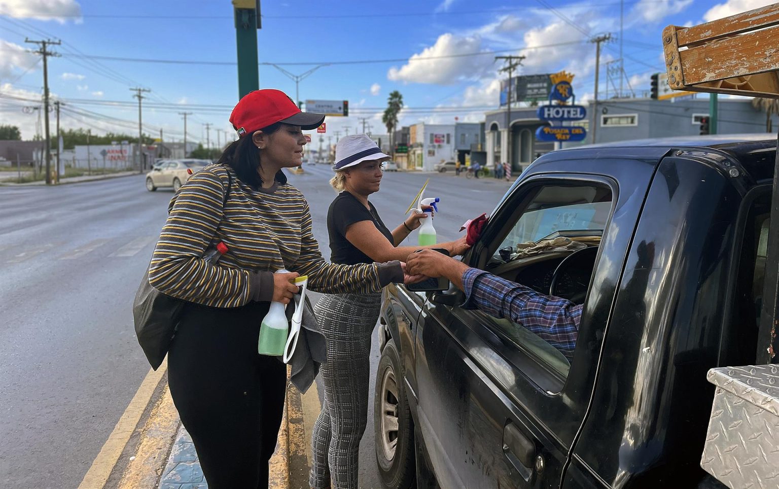 Dos mujeres limpian los vidrios de un vehículo el 11 de noviembre de 2022, en Matamoros (México). EFE/ Abraham Pineda Jácome
