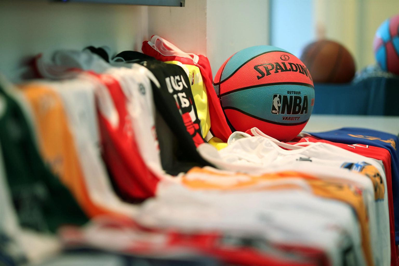 En la imagen un registro de archivo de un balón con el logo de la NBA, junto a varias de las camisetas que distinguen a los equipos de la Asociación Nacional de Baloncesto estadounidense. EFE/Raúl Martínez