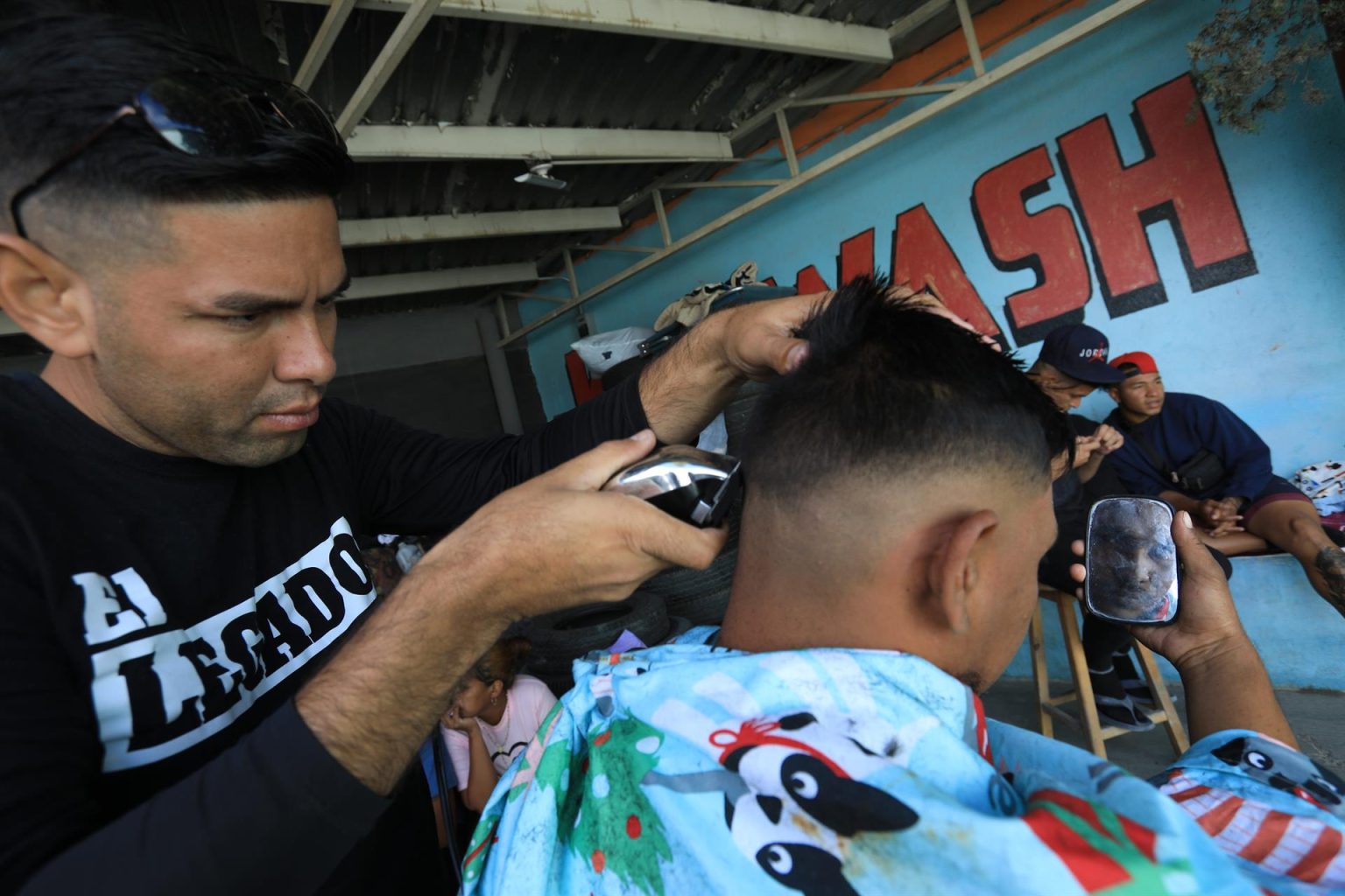 El migrante de origen venezolano, José Miguel Ceballos, corta el cabello a una persona el 11 de noviembre de 2022 en Ciudad Juárez, Chihuahua (México). EFE/Luis Torres