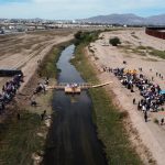 Fotografía aérea que muestra migrantes de diversas nacionalidades, mientras participan en una misa binacional a mitad del Río Bravo hoy, en Ciudad Juárez, estado de Chihuahua (México). EFE/Luis Torres
