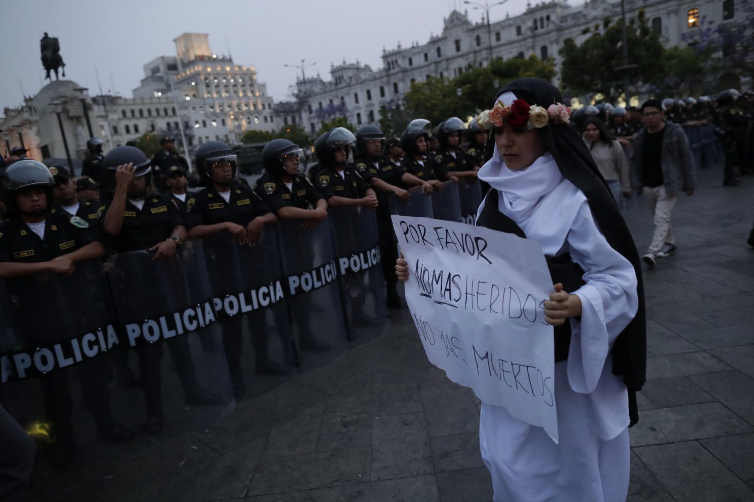 Una mujer con un cartel con un mensaje de paz camina frente a policías en la Plaza de San Martín, donde confluyeron manifestantes opositores al Gobierno y simpatizante a este durante la denominada "Marcha por la Paz", hoy, en Lima (Perú). EFE/ Bienvenido Velasco