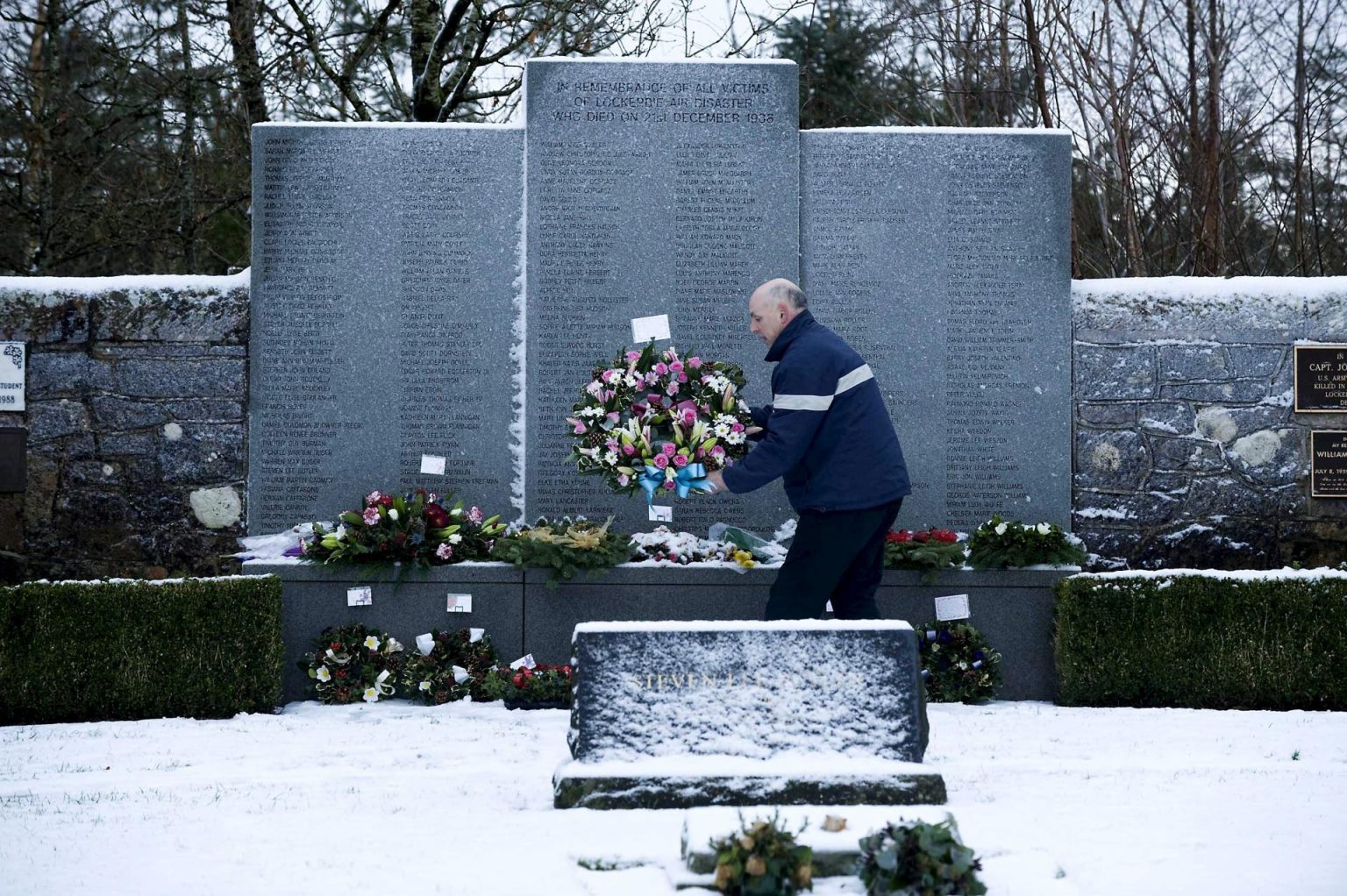Un hombre transporta un arreglo floral en el parque conmemorativo a las víctimas del atentado de Lockerbie, en el cementerio de Dryfesdale en Lockerbie, Reino Unido. Imagen de archivo. EFE/BRIAN STEWART