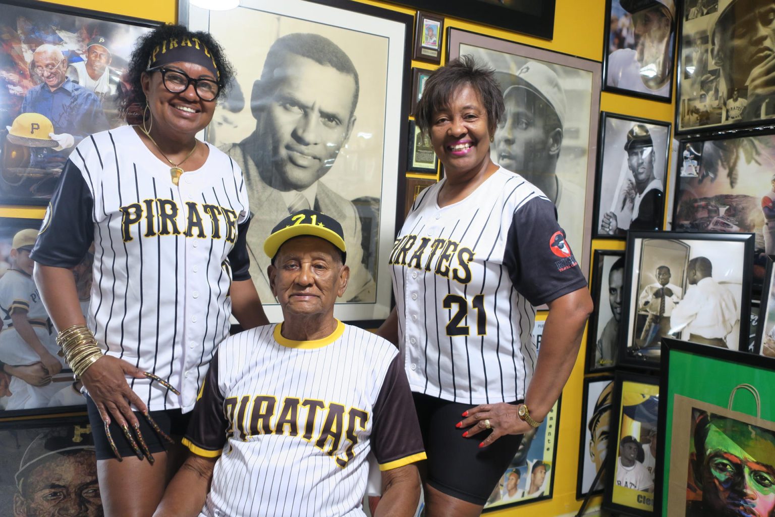 Fotografía que muestra las hijas de Justino Clemente Walker, Judith (i) y Janet Clemente (d), mientras abrazan a su padre en el pequeño museo que tienen dedicado a Roberto Clemente en su residencia, el 23 de diciembre de 2022 en Carolina (Puerto Rico). EFE/Jorge Muñiz