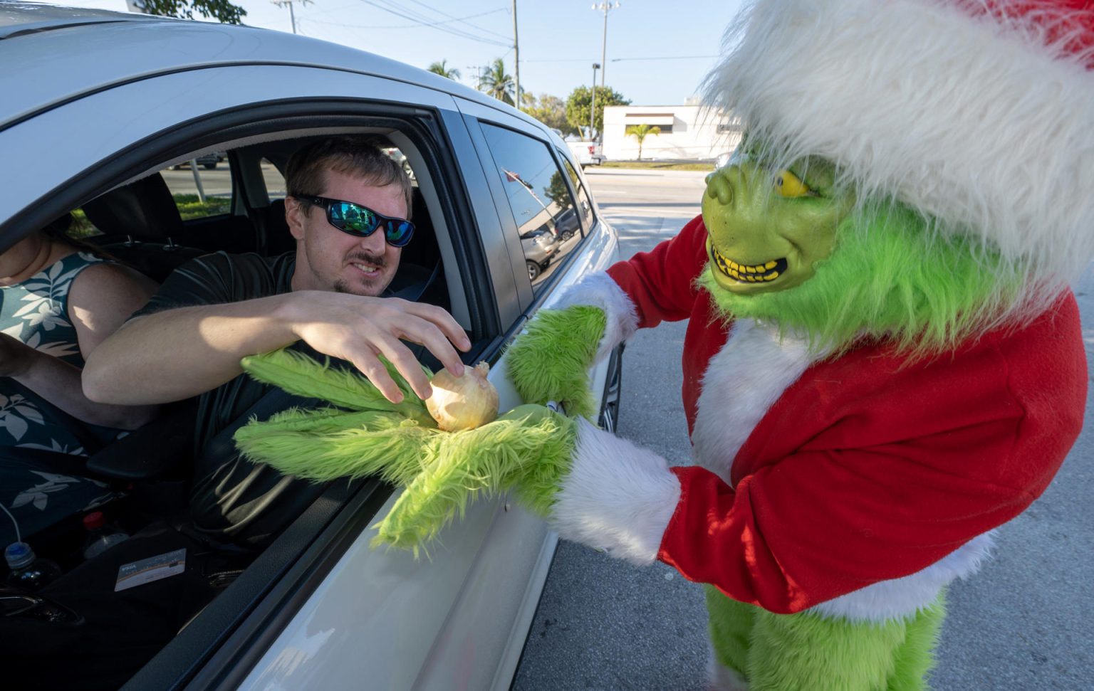 Fotografía cedida por la Oficina de noticias de los Cayos de Florida donde aparece el coronel de la oficina del alguacil del condado de Monroe, Lou Caputo, disfrazado de Grinch, mientras entrega una cebolla a un conductor a cambio de una multa, en la autopista Florida Keys Overseas hoy, en Marathon, Florida (Estados Unidos). EFE/ Andy Newman /Florida Keys News Bureau/ SOLO USO EDITORIAL/ SOLO DISPONIBLE PARA ILUSTRAR LA NOTICIA QUE ACOMPAÑA (CRÉDITO OBLIGATORIO)