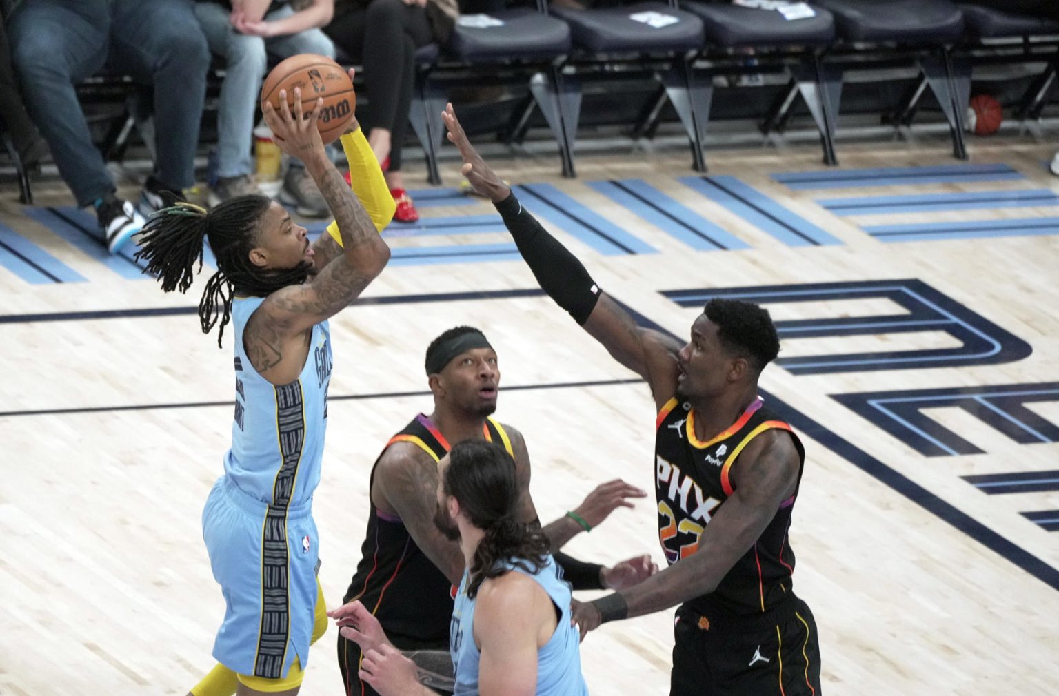 Ja Morant (i), base de los Grizzlies de Memphis, fue registrado este lunes, 16 de enero, al lanzar un balón al aro, ante la marca de Deandre Ayton, de los Suns de Phoenix, durante un partido de la NBA, en el coliseo FedEx Forum, en Memphis (Tennessee, EE.UU). EFE/Karen Pulfer