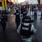 Comerciantes limpian las calles bajo el resguardo de la policía municipal y Guardia Nacional (GN) tras un operativo contra el comercio ambulante de migrantes hoy, en la ciudad de Tapachula, estado de Chiapas (México).  EFE/Juan Manuel Blanco