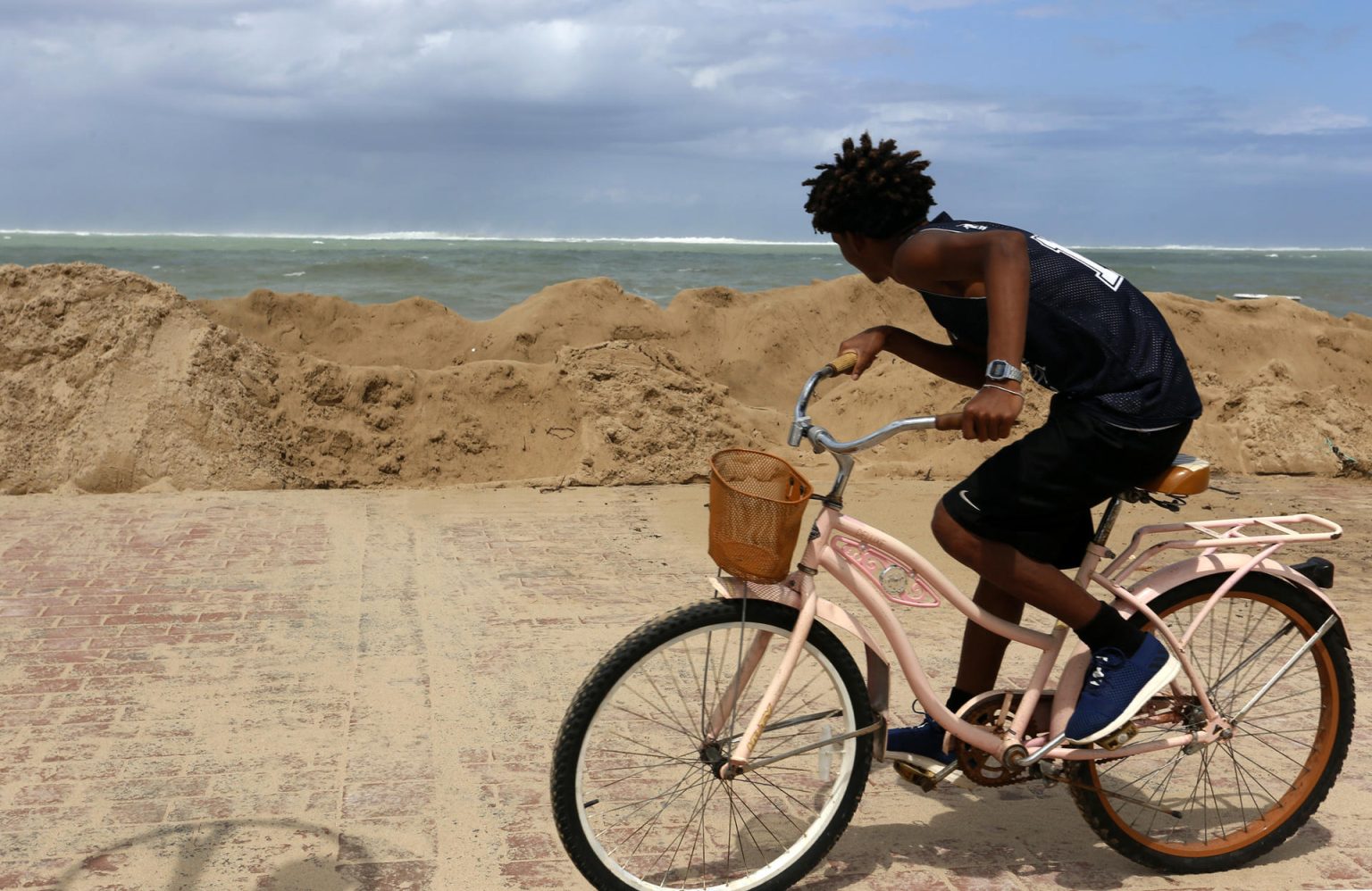 Fotografía de archivo que muestra a un joven que monta bicicleta mientras observa las altas olas en San Juan, Puerto Rico. Inicio de archivo. EFE/Thais Llorca