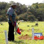 El líder comunitario de los haitianos en Puerto Rico, Leonard Prophil, coloca una bandera nacional durante una vista el lunes 23 de enero al cementerio de San Juan, Puerto Rico. EFE/Thais Llorca