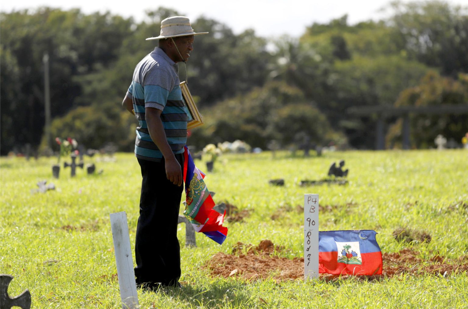 El líder comunitario de los haitianos en Puerto Rico, Leonard Prophil, coloca una bandera nacional durante una vista el lunes 23 de enero al cementerio de San Juan, Puerto Rico. EFE/Thais Llorca