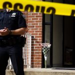 Un ramo de flores permanece detrás de un oficial de policía de Nueva York que presta guardia a un edificio donde cuatro personas fueron encontradas sin vida, en Nueva York (EE.UU.). Imagen de archivo. EFE/Justin Lane