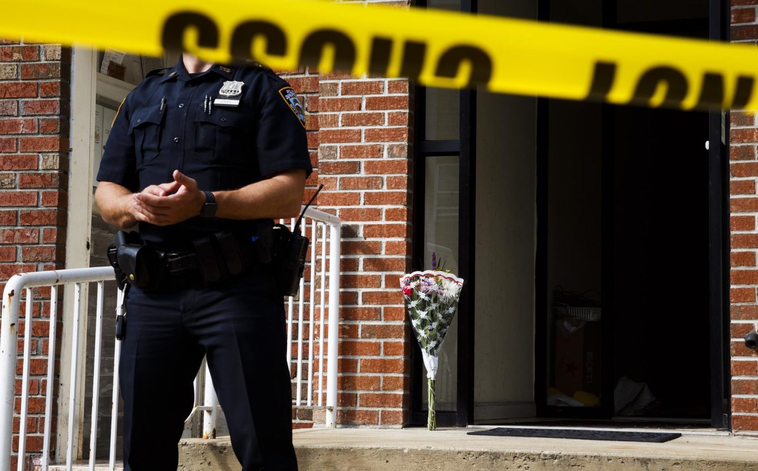 Un ramo de flores permanece detrás de un oficial de policía de Nueva York que presta guardia a un edificio donde cuatro personas fueron encontradas sin vida, en Nueva York (EE.UU.). Imagen de archivo. EFE/Justin Lane