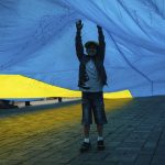 Un niño refugiado juega con una bandera ucraniana en Kiev (Ucrania). EFE/Roman Pilipey