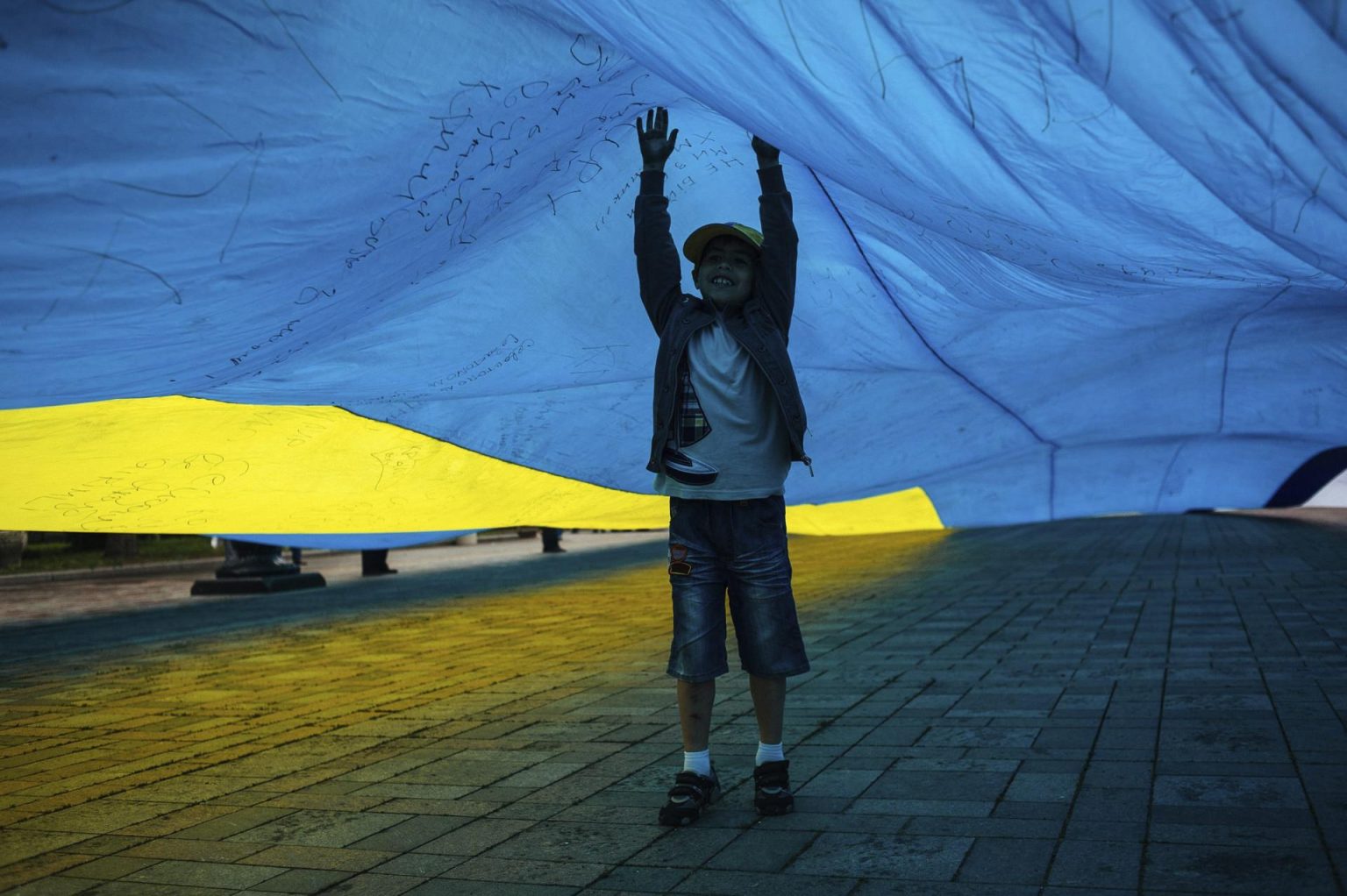 Un niño refugiado juega con una bandera ucraniana en Kiev (Ucrania). EFE/Roman Pilipey