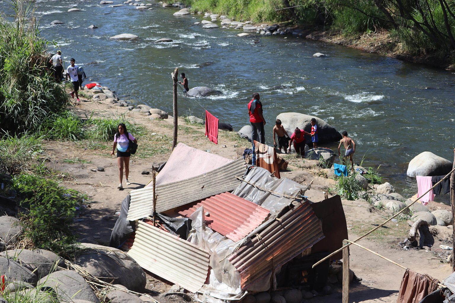 Grupos de personas migrantes se establecen en un campamento improvisado a orillas del Río Coatán hoy, en la ciudad de Tapachula, estado de Chiapas (México). EFE/Juan Manuel Blanco