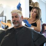 La estilista Haydeliz Cruz pinta de rubio la cabellera de Carlos Miranda, que decidió cambiar de color su cabello en respaldo al "Team Rubio", el 8 de marzo de 2023, en su residencia en Dorado (Puerto Rico). EFE/ Jorge Muñiz