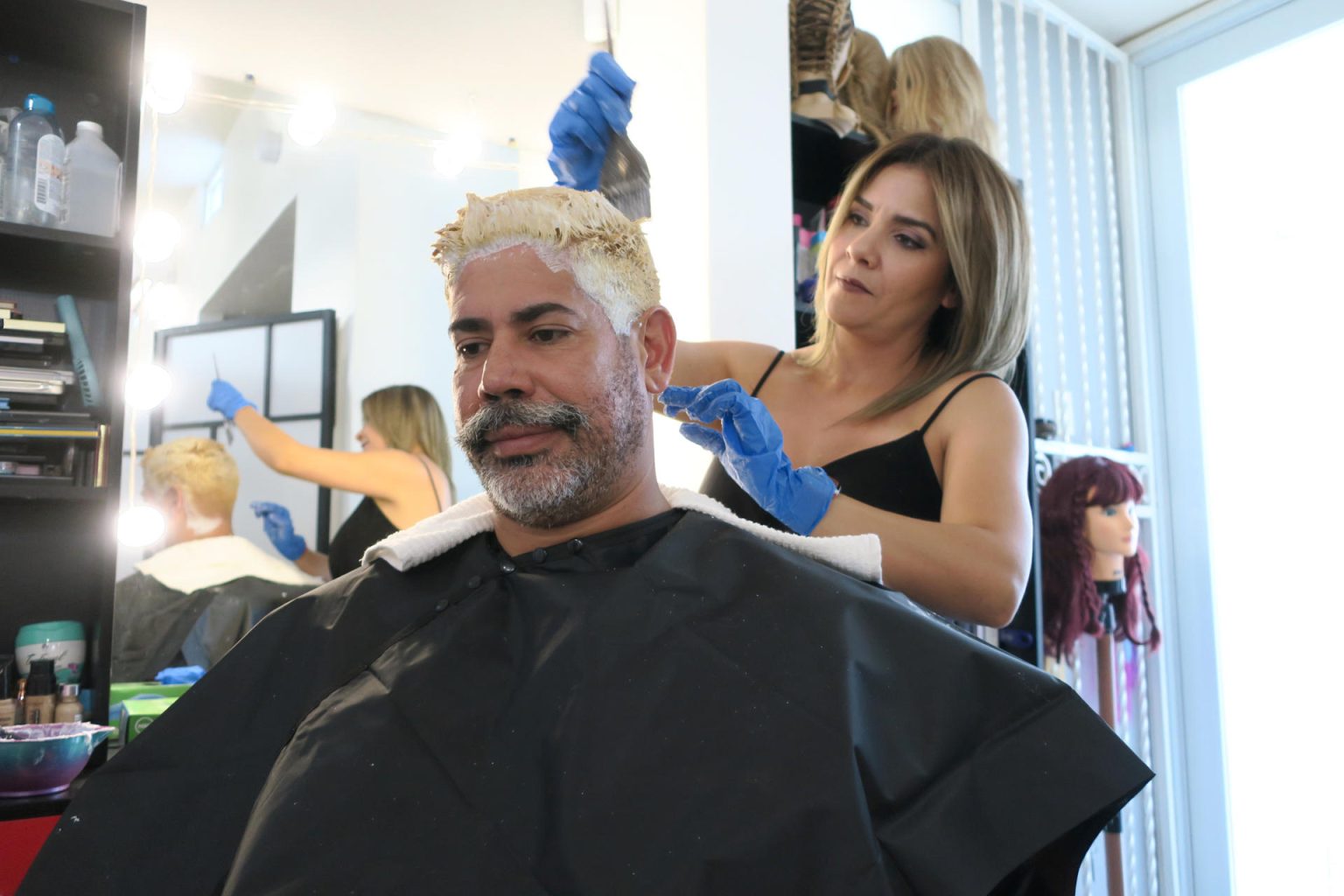 La estilista Haydeliz Cruz pinta de rubio la cabellera de Carlos Miranda, que decidió cambiar de color su cabello en respaldo al "Team Rubio", el 8 de marzo de 2023, en su residencia en Dorado (Puerto Rico). EFE/ Jorge Muñiz