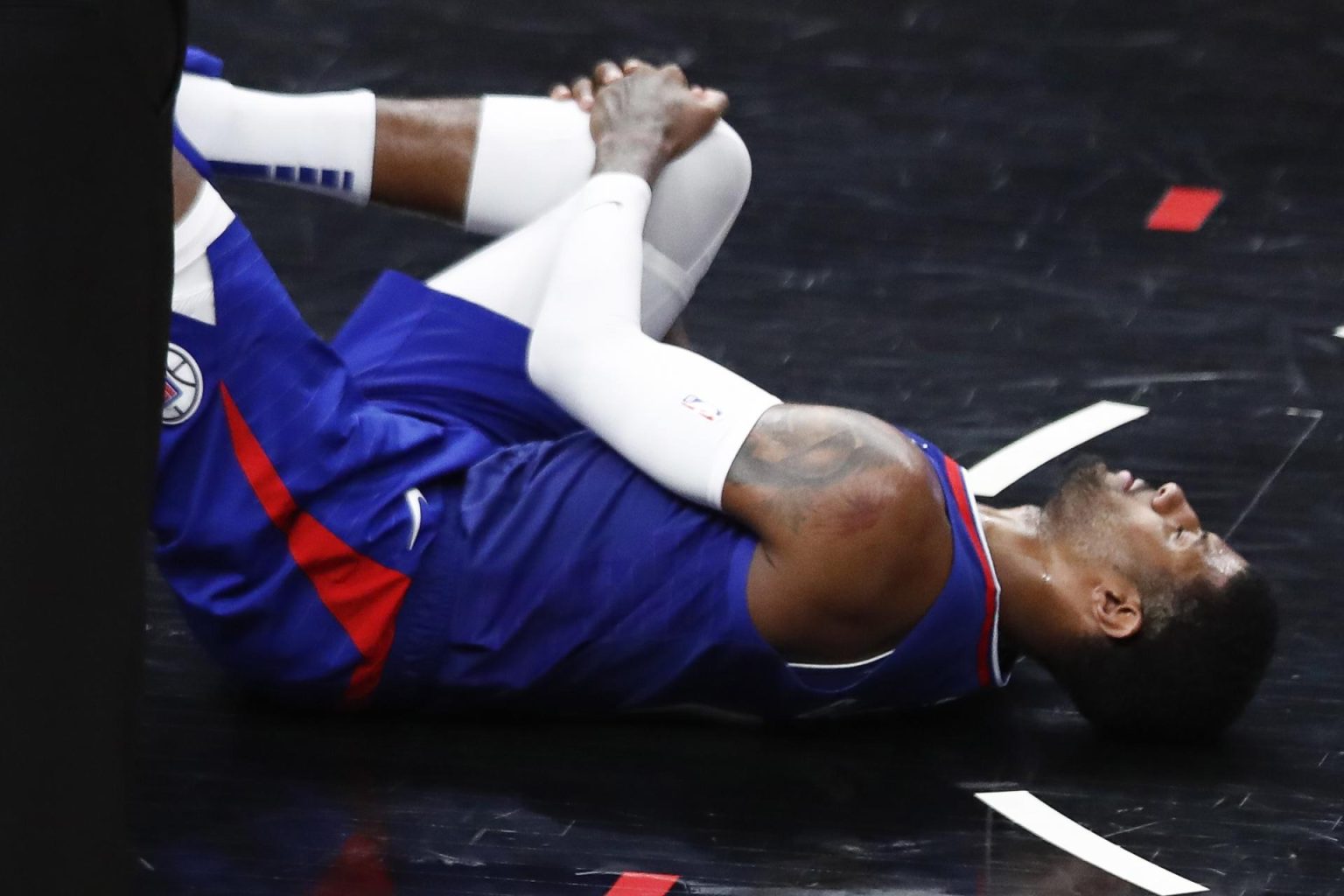 Paul George de Los Angeles Clippers permanece en el piso tras sufrir una lesión en su rodilla ante los Oklahoma City Thunder en el Crypto.com Arena, en Los Ángeles, California (EE.UU.), este 21 de marzo de 2023. EFE/EPA/Caroline Brehman