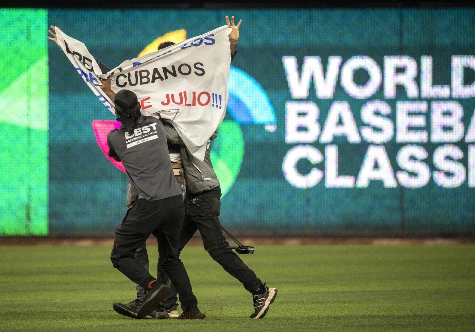 Un manifestante fue registrado este domingo, 19 de marzo, al ser detenido, luego de ingresar al campo de juego con una pancarta en contra del Gobierno de Cuba, durante una de las semifinales del Clásico Mundial de Béisbol disputada entre Estados Unidos y Cuba, en el estadio LoanDepot Park, en Miami (Florida, EE.UU.). EFE/Cristóbal Herrera